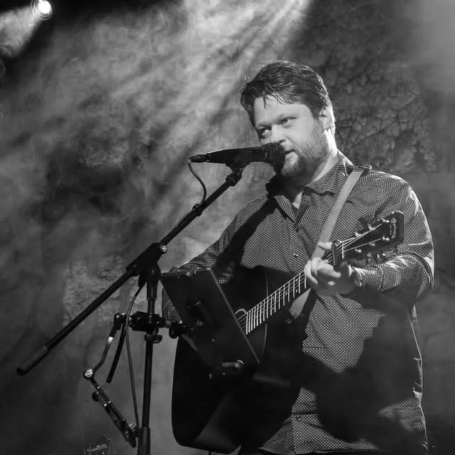 Hendrik Thiel singt auf einer Bühne und spielt Gitarre