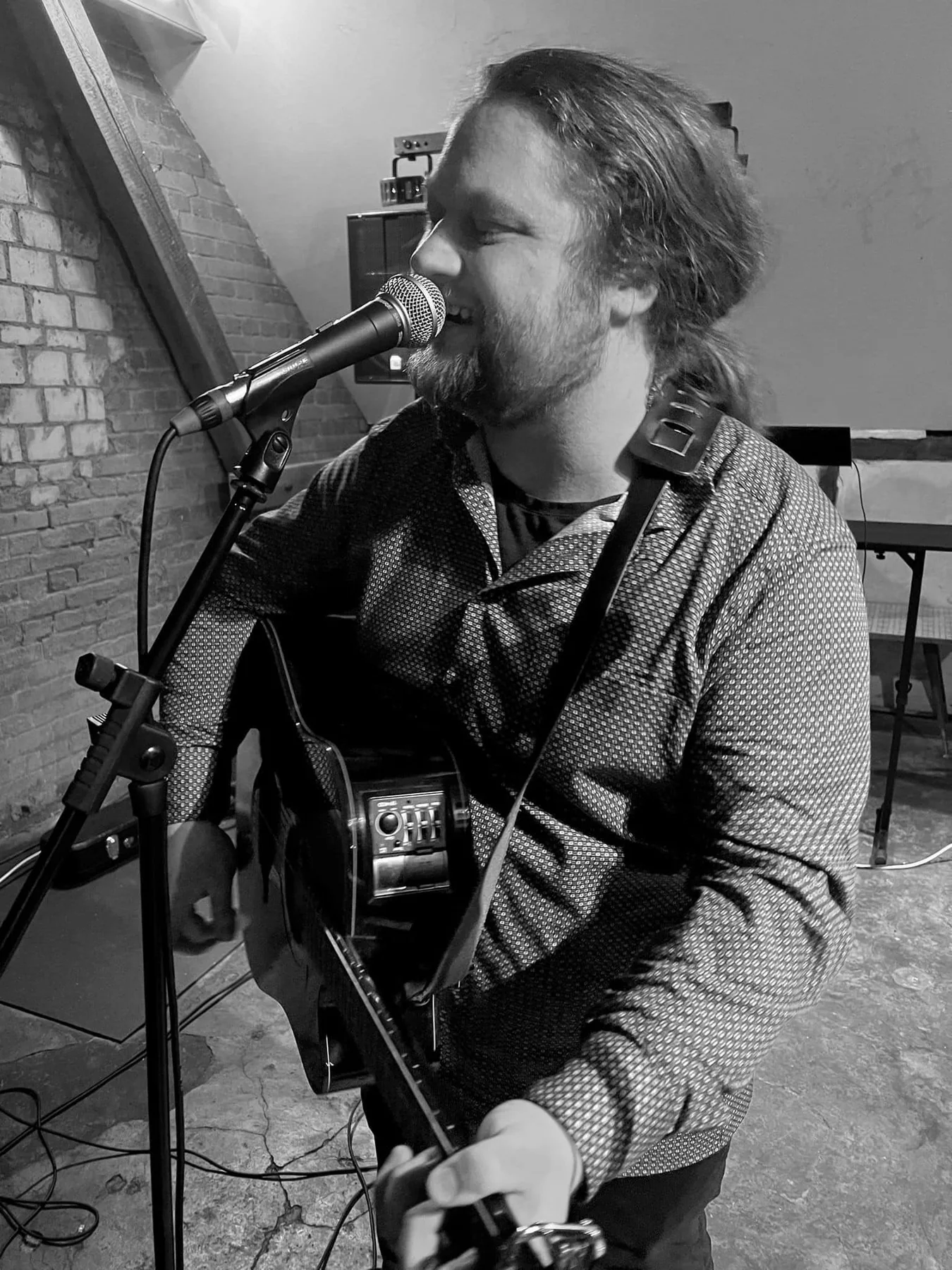 Hendrik Thiel singt in ein Mikrofon und spielt akustische Gitarre